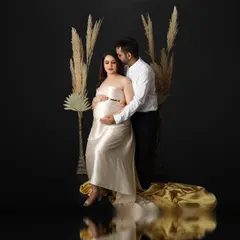 I created this fine art maternity portrait using a dark, reflective floor and dramatic lighting. The expecting mother is seated, wearing a satin gown that pools around her, creating a look of pure elegance.