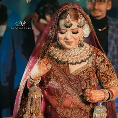 A beautiful candid shot of the bride during her entrance. Her shy smile and the details of her maroon velvet lehenga and heavy jewelry are captured perfectly.
