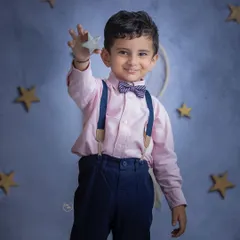 Dressed smartly in a bowtie and suspenders, this little boy holds up a star against a dreamy, night-sky backdrop. Themed studio sessions like this are a wonderful way to bring a child's imagination to life.