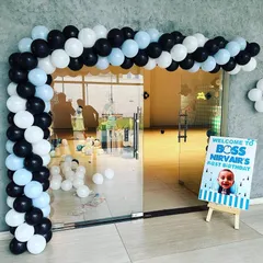 A stylish black, white, and blue balloon arch creating an inviting entrance for a Boss Baby themed party. A personalized welcome sign greets guests as they arrive.