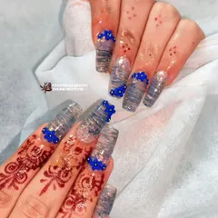 This design combines a translucent, wavy pattern with clusters of tiny, hand-sculpted blue flowers. The 3D floral details add a pop of color and texture to these long, square extensions.
