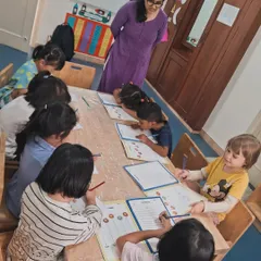 An educator guides a group of older children through a pre-writing worksheet. We use fun, structured activities like this to help them develop the fine motor control needed for writing letters and numbers.