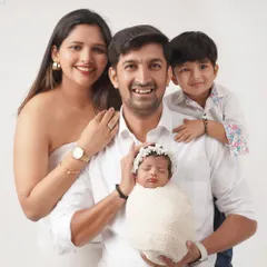 A classic family portrait with parents, a proud big brother, and the new baby sister. Everyone is smiling for the camera, creating a perfect memory to cherish.