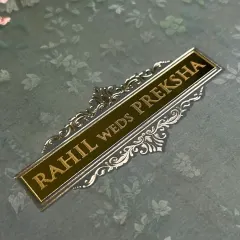 A close-up on the gold and silver foil nameplate, set against a subtle floral background, showcasing the blend of texture and shine.