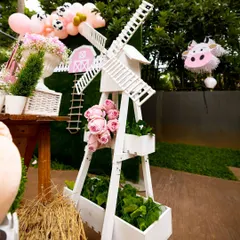 Every detail is thoughtfully designed, like this decorative white windmill that adds an authentic touch to the farm theme. It's paired with fresh flowers and greenery to enhance the rustic, charming atmosphere of the party.