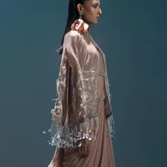 A side profile of a model in a contemporary draped saree with a heavily embellished jacket. The styling focuses on the unique texture and feather details of the jacket, creating a look that is both modern and glamorous.