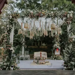 A view of the mandap at the Pond Pavilion, adorned with pastel flowers and intricate hanging decor, creating a fairytale setting.