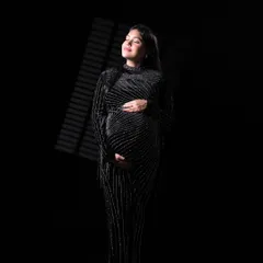 A dramatic, fine art portrait using "window blind" lighting. The play of light and shadow on the sparkling black gown creates a sophisticated and mysterious mood.