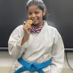 The joy of achievement. A blue-belt student bites her gold medal, a reward for her hard work and excellent performance in a recent competition.