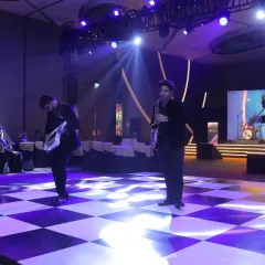 Our team of musicians, including a violinist and keytarist, performing a flashmob on a checkered dance floor during a corporate party.