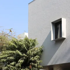 A detail of the minimalist facade of the Jaipur House, showing the clean lines of a punched window. This simple gesture creates a strong graphic composition against the textured white wall.