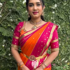 My client Kshipra shines in this vibrant hot pink and orange silk blouse. I designed it with a traditional fitted silhouette and detailed gold zari work to perfectly complement her heritage saree, creating a look of pure elegance.