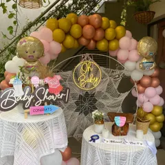 A charming and rustic 'Oh Baby' baby shower setup. This decoration features a macrame backdrop, a multi-colored balloon arch, and themed props for a gender-neutral celebration.