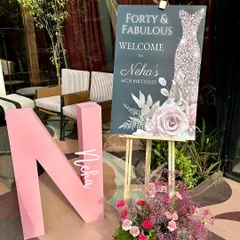 A personalized welcome area for the "Forty & Fabulous" celebration. It features a custom welcome sign on an easel, a large pink initial "N" for the birthday girl, and a beautiful fresh floral arrangement.