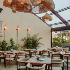 This bright and airy seating area under a skylight features patterned tabletops and oversized rattan pendant lights, creating a perfect daytime dining spot.
