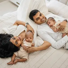 A happy family of four relaxing on the bed. This at-home lifestyle shot with twins is full of joy and natural connection, capturing a perfect family moment.