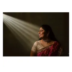 A creative portrait using a single beam of light during a Haldi shoot. This technique creates a dramatic, spotlight effect, highlighting the bride's profile and the rich colors of her bandhani saree.