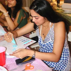A guest at our workshop carefully practicing her buttercream piping techniques on a guide sheet before starting on her cake.