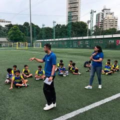 A sports psychologist from our partner Mpower Minds gives a talk to our young players, who are seated on the pitch. This session is part of our holistic approach to player development.