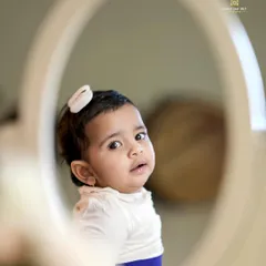 A sweet sitter session moment. This baby girl's curious expression is perfectly captured in the reflection of a mirror.