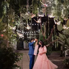 A fairytale-like engagement shoot at night. The couple dances under trees adorned with fairy lights and butterfly decorations, creating a truly magical and romantic scene.