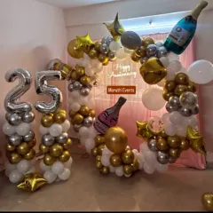 Celebrating a silver anniversary in style. This elegant setup for a 25th anniversary features a beautiful balloon arrangement in gold, silver, and white, complete with large number balloons and champagne bottle props to mark the special milestone.