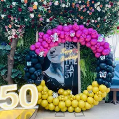 A unique and artistic setup for a 50th birthday, with a multi-colored balloon ring and a modern art backdrop.