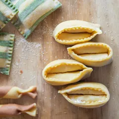 The art of fresh pasta. Here you can see the delicate shapes of our doppio agnolotti and striped ravioli, all made by hand in our kitchen daily. This is the foundation of many of our signature dishes.