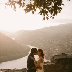 A romantic kiss overlooking a winding river and valley in Georgia. The hazy, sun-drenched landscape creates a soft, dreamy backdrop for this intimate moment.