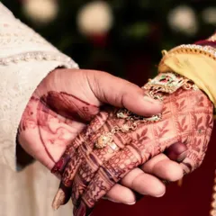 A close-up of the couple's hands joined during the wedding ceremony. This image, focusing on the bride's intricate mehndi and the way their hands are held, symbolizes their union and the promises being made.