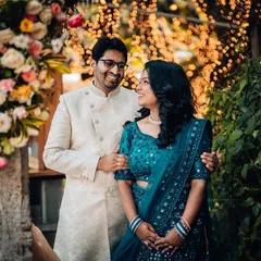 A classic reception portrait of a couple, smiling at each other in front of a beautiful floral and light-filled backdrop.