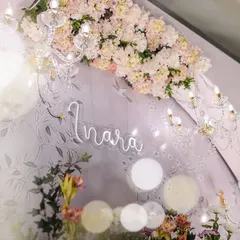 A detail shot of the neon sign with baby Inara's name, set against the floral backdrop and sparkling chandeliers. This modern touch added a personalized and celebratory element to the decor.