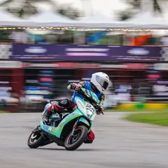 A rider on an Ather 450X leans into a turn during the EV racing festival, captured with a motion blur to emphasize the speed.