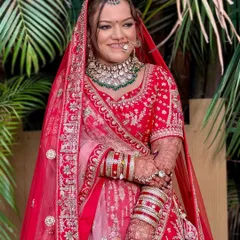A full-length view of this stunning bride in her traditional red lehenga. The soft glam makeup with defined eyes ensures her face is the focal point, radiating pure joy and elegance.