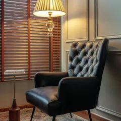 This reading nook within the office features a comfortable tufted leather armchair and a classic floor lamp. It’s a perfect example of how I like to incorporate residential-style comfort into a commercial setting, making the space feel more welcoming.