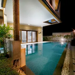 This residential pool is designed for evening enjoyment, with underwater lights and strategically placed landscape lighting. The covered patio area provides a comfortable space to relax by the water, day or night.