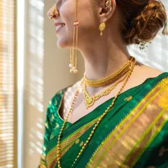 A close-up on the details of the Marathi bridal look. Here you can see the layered gold necklaces, the classic nath, and the intricate design of the green Paithani saree.