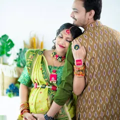 A tender moment between a couple in traditional attire. The mom-to-be rests her head on her partner's shoulder, both dressed in beautiful, coordinating ethnic wear.
