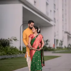 A portrait of an expecting couple in traditional attire. The way they hold the baby bump together shows their shared excitement for the new arrival.