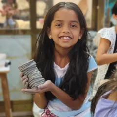 A young girl proudly holds up the vase she made using the coil-building technique. Our kids' classes teach fundamental hand-building skills in a fun and accessible way.
