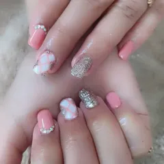 A very detailed and decorative set. It features a mix of pink polish, silver glitter, a white quilted pattern, and rhinestones at the base of the nails.