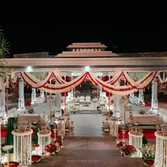 The wedding mandap illuminated at night, showcasing the intricate floral work, traditional draping, and the warm glow of brass lamps.