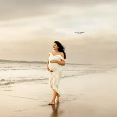 Sun, sea, and the sweetest wait. A solo walk along the shoreline, with the wind in her hair and hands on her bump. This image captures the feeling of peaceful anticipation.