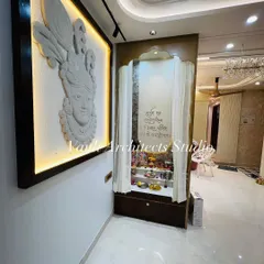 A close-up of the finished pooja corner. The intricately carved Krishna mural is illuminated with warm backlighting, creating a divine ambiance next to the custom-built mandir with delicate curtains.