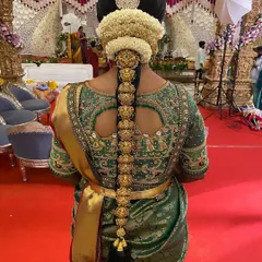 This is a perfect example of a grand bridal braid for a Muhurtham. The entire length is covered with intricate gold Jada Billa, set against a backdrop of fresh jasmine flowers, creating a look of pure opulence.