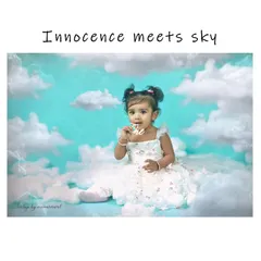 A dreamy and innocent portrait of a baby girl sitting among fluffy white clouds against a sky-blue background, creating a magical, heavenly scene.
