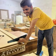 Precision in progress. Here, one of our craftsmen is working on the intricate details of a furniture piece, ensuring every joint and finish meets our high standards of quality.