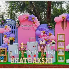 Shathakshi's first birthday was a beautiful butterfly wonderland. This outdoor setup includes pink and purple backdrops, large butterfly wing props, and a lush green base, making it a perfect photo spot.