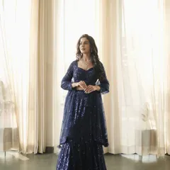 Another full-length shot of the blue sequin lehenga, captured against elegant sheer curtains to create a soft, dreamy effect.