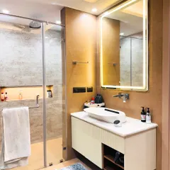 A clean and contemporary bathroom with a floating vanity, a vessel sink, and a large backlit mirror. The walk-in shower with a glass partition makes the space feel open and bright.